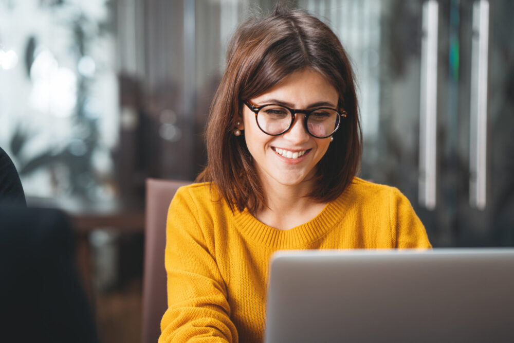 Portrait of happy business woman wearing glasses at workplace in office.